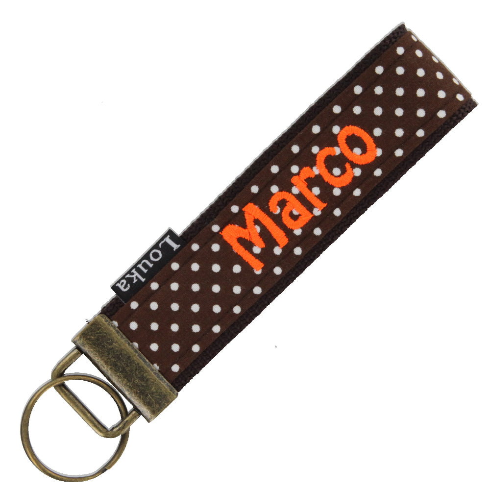 Handgemaakte Louka pols sleutelhanger in bruin met kleine witte stippen, personaliseerbaar met naam en hardware, formaat 13×3 cm.